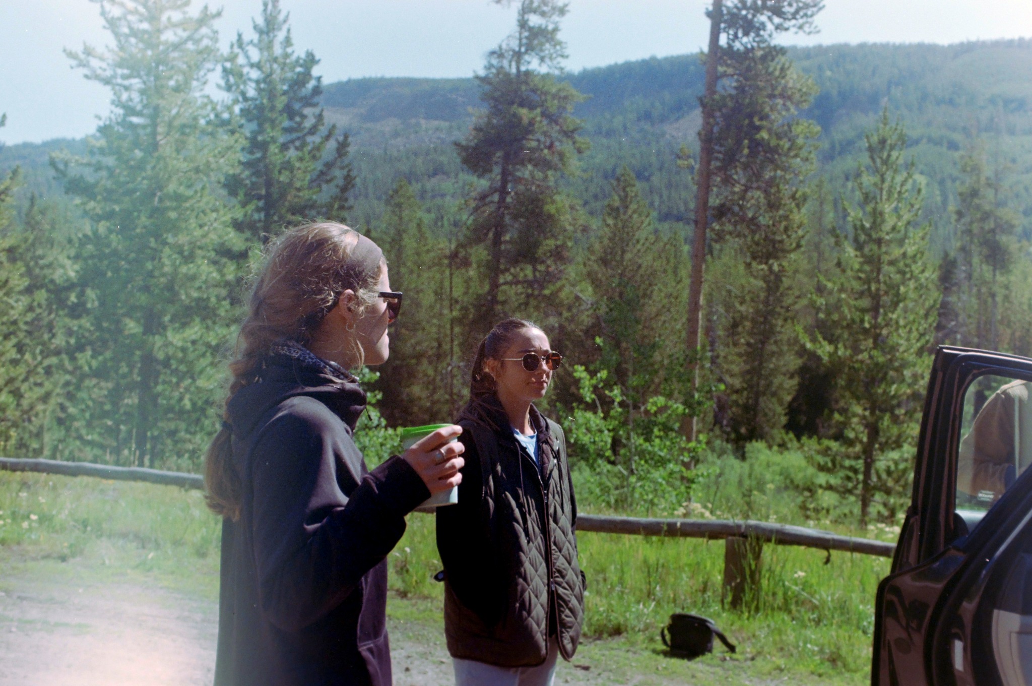 Two people standing beside a vehicle with a mountain behind them