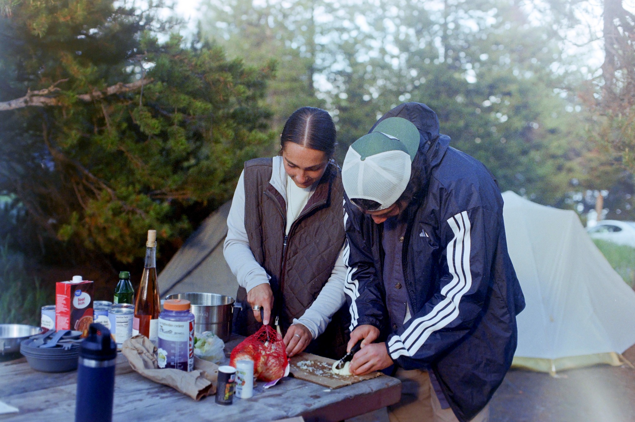 Two people preparing food at a campsite